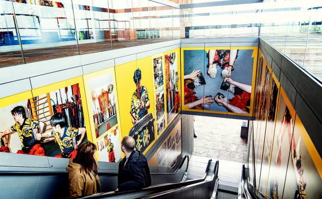 Mensen op roltrap kijken naar foto expo