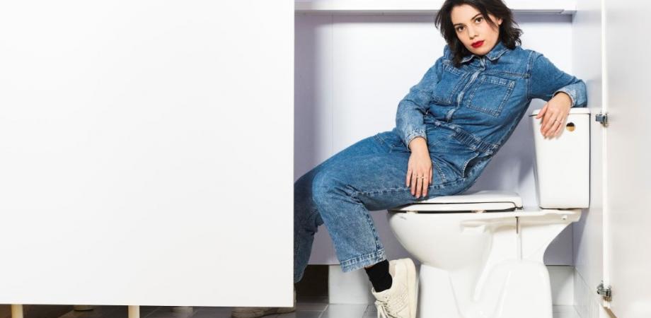 Karen François dame in jeansoverall zit op een toilet
