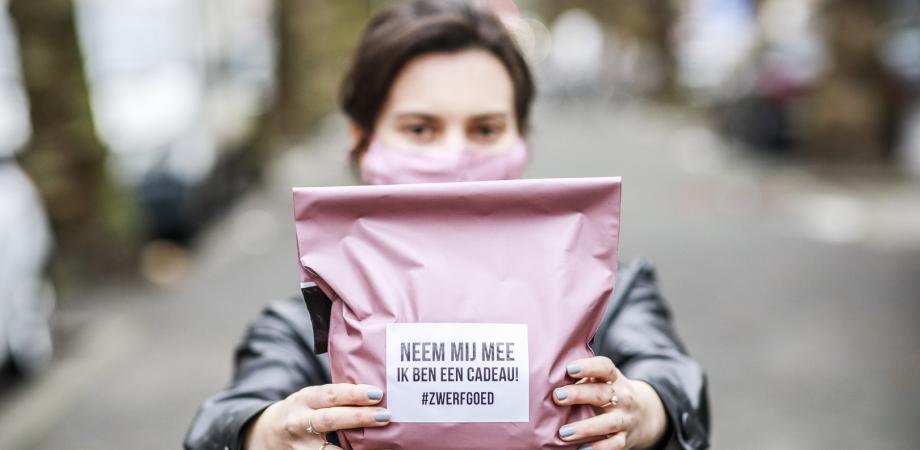 Zwerfgoed dame houdt een pakje voor zich met opschrift Neem mij mee ik ben een cadeau #zwerfgoed